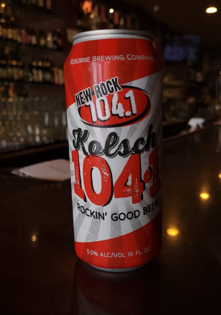 A Can of New Rock 104.1 Kolsch by Reborne Brewing Company is displayed on the bar top of bog house pub in Fresno California